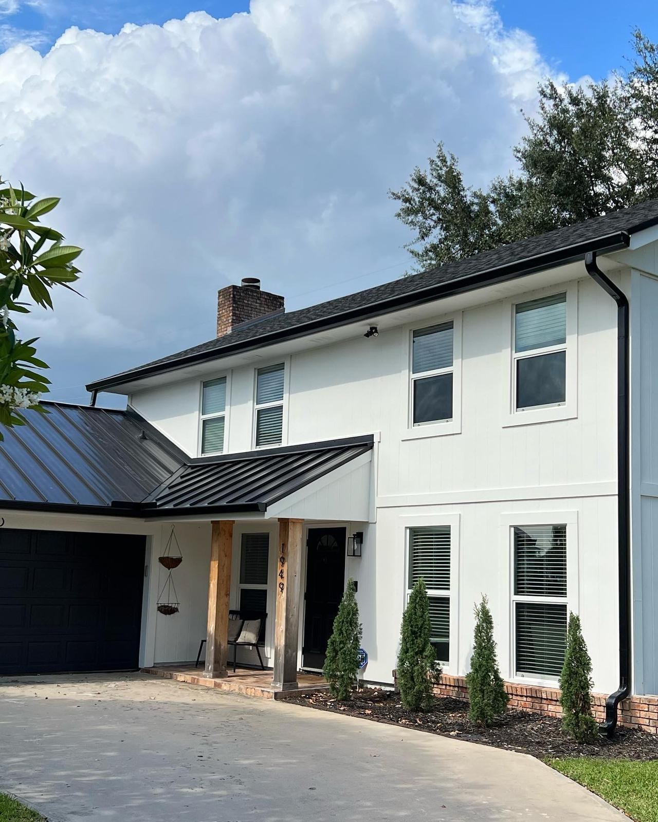 Black aluminum gutters and downspouts on a modern two-story home with white siding