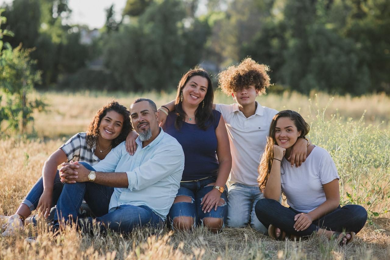 Warren and Lynette Hall with their three children, seated together in a sunlit field