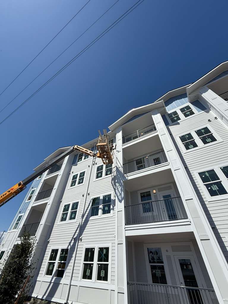 Certified Gutters crew working from a boom lift on the gutters of a three-story apartment building
