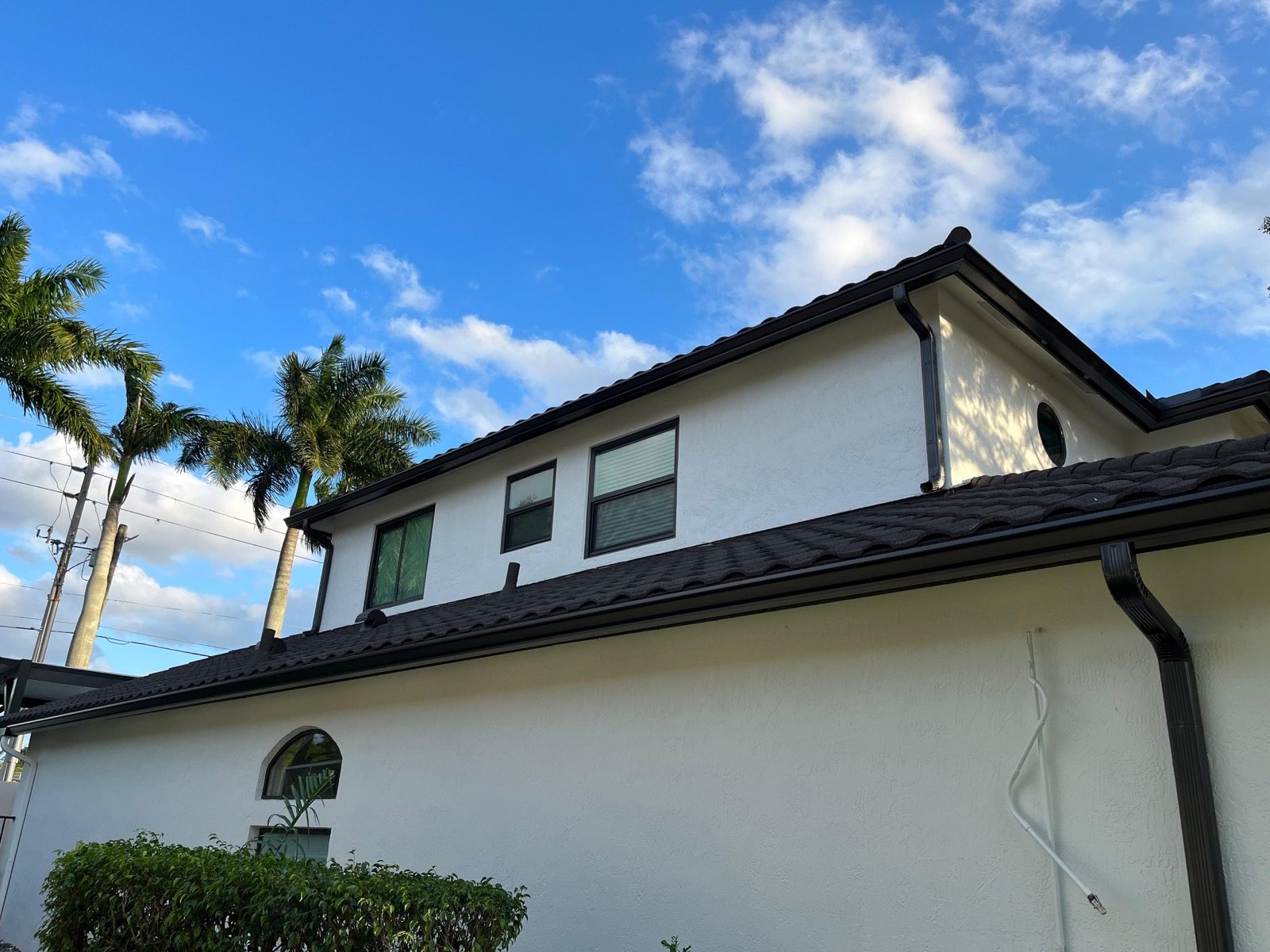 Dark bronze seamless gutters on a two-story home with a barrel-tile roof