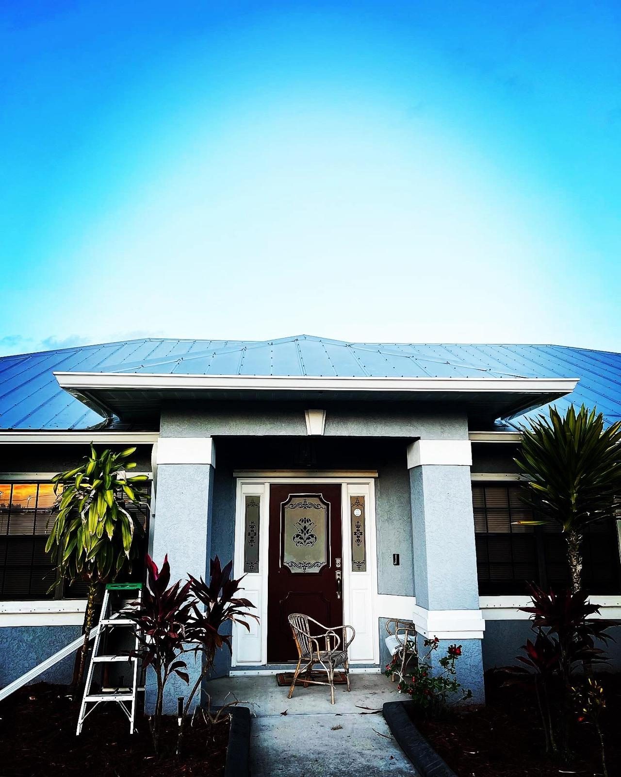 Seamless gutters along the eaves of a hip-roof home with tropical landscaping