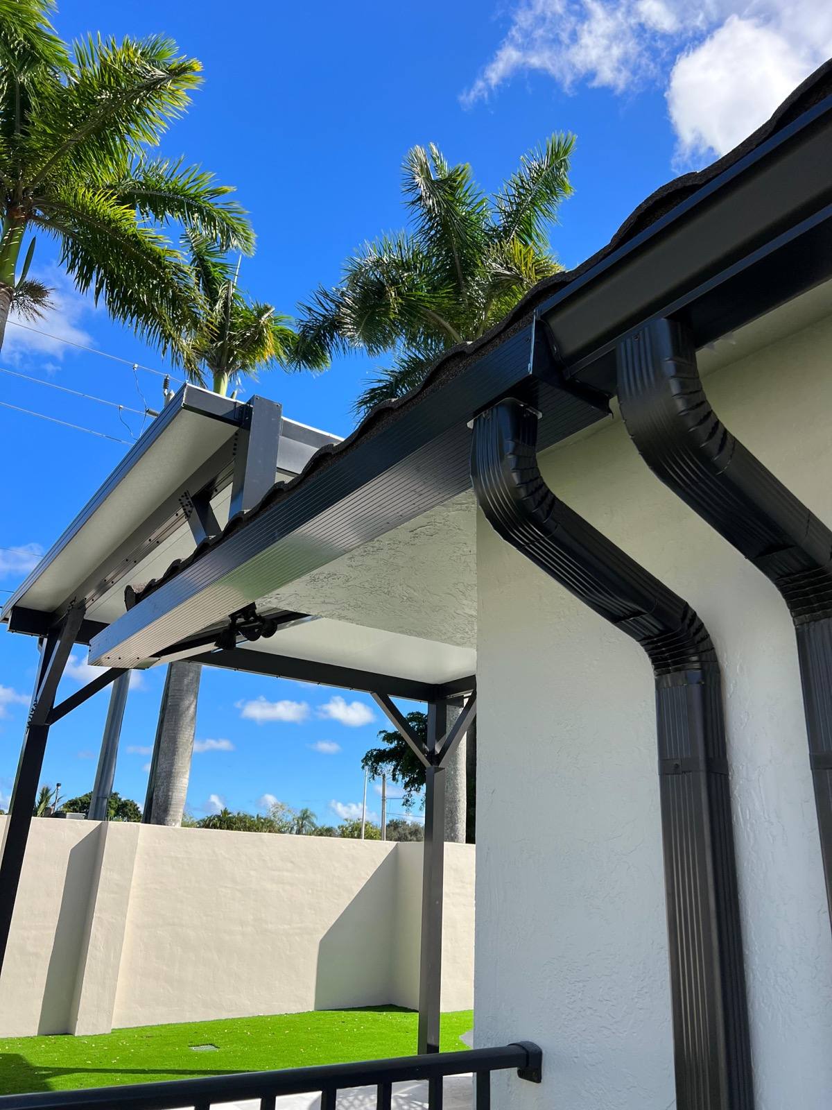 Dark bronze K-style aluminum gutter and corrugated downspouts installed on a single-story Florida home