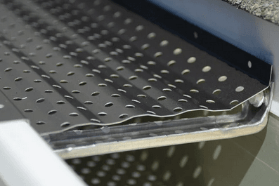 Close-up of a perforated aluminum gutter guard panel installed inside a K-style gutter