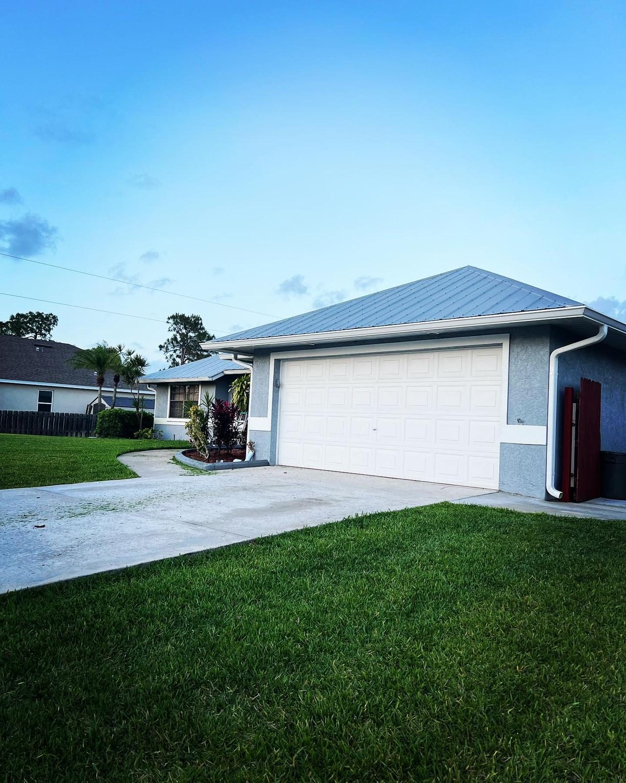 Single-story stucco garage with a metal roof and seamless aluminum gutters along the eave