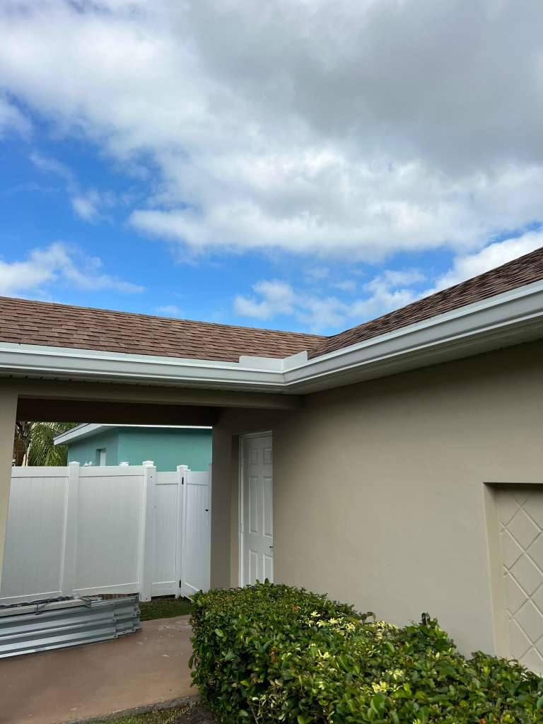 White seamless aluminum gutters along the hip-roof eave of a single-story Florida home