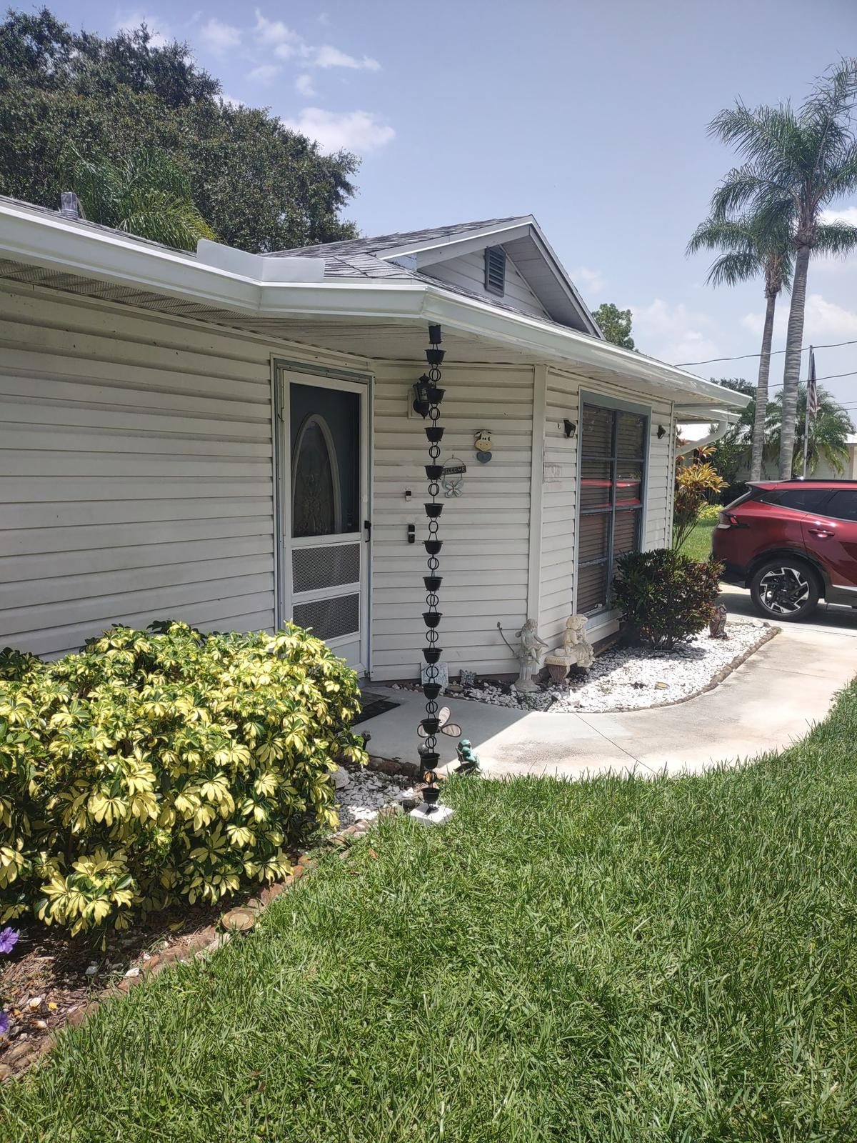 White seamless aluminum gutters on a single-story ranch home with a decorative rain chain in place of a downspout