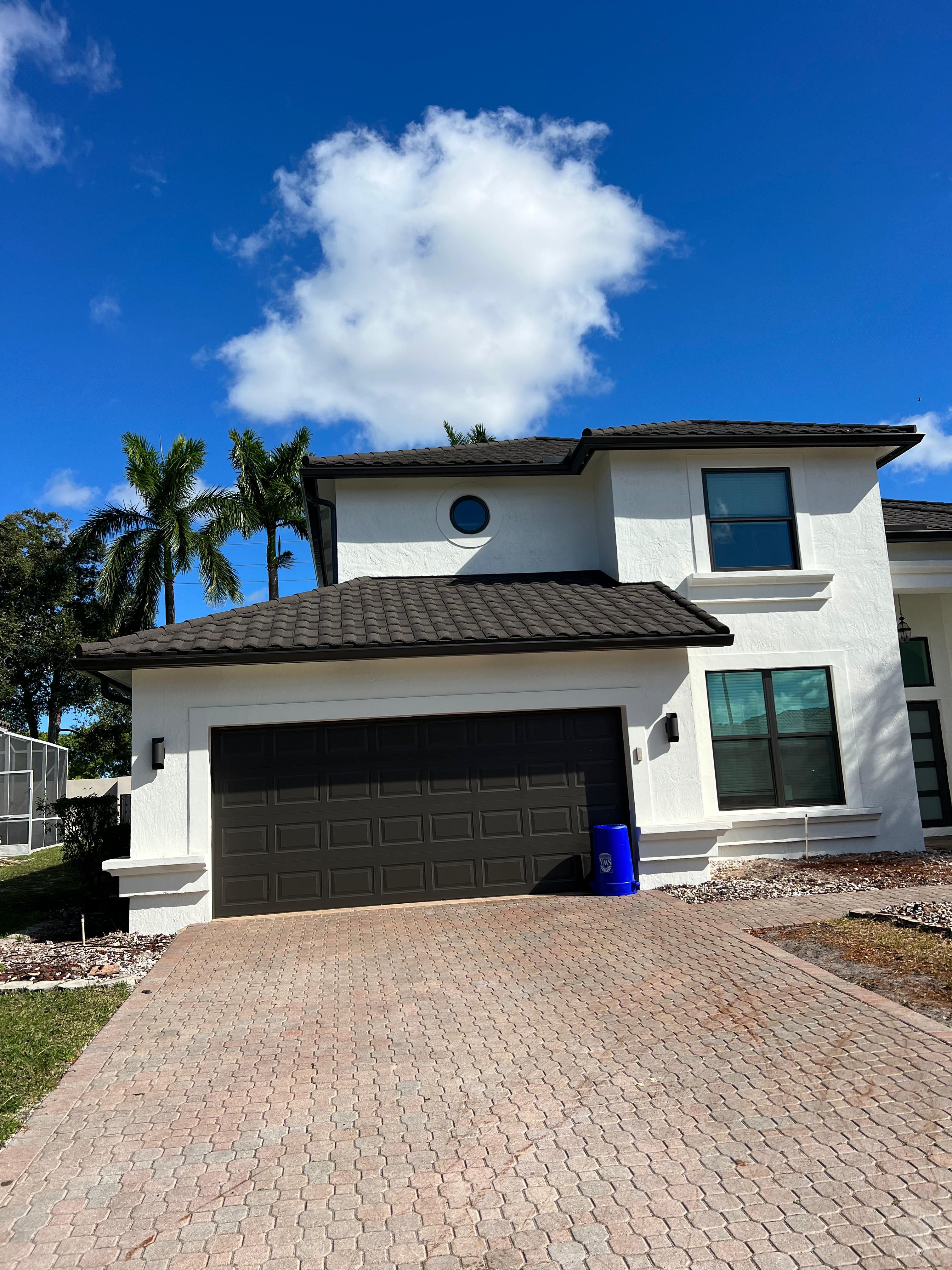 White gutters and downspouts on a two-story home with a dark tile roof