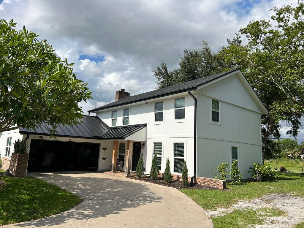 Wide view of a white two-story home with seamless aluminum gutters along the roofline